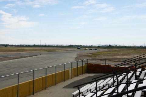 1995 Ford Taurus - Cars race on a track with bleachers visible in the foreground under a partly cloudy sky.