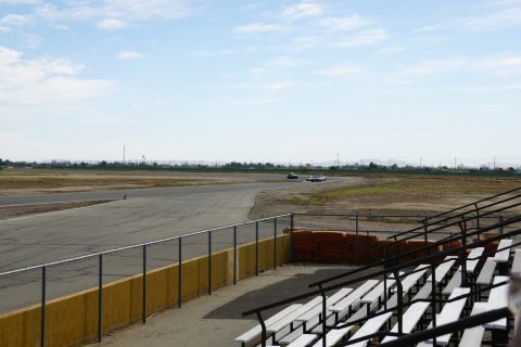 1995 Ford Taurus - Two cars race on a track with grandstands in the foreground and a distant horizon.