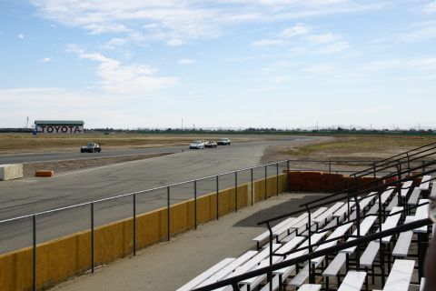 1995 Ford Taurus - Cars race on a track with a Toyota building visible and bleachers in the foreground.