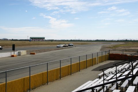 1995 Ford Taurus - Cars race on a track with a large Toyota sign visible in the distance under a cloudy sky.