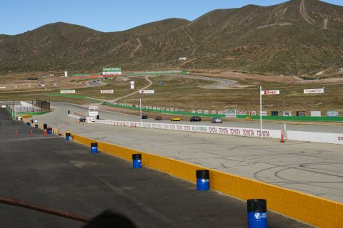 1995 Ford Taurus - Cars on a race track at Willow Springs, with mountains and Toyota advertisements visible.