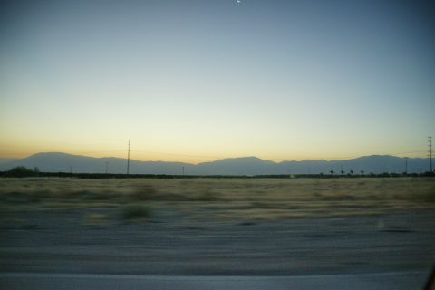 1995 Ford Taurus - A vast desert landscape unfolds under a fading sky, with distant mountains silhouetted against the horizon.