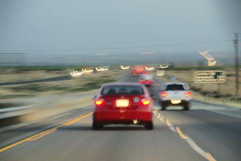 1995 Ford Taurus - Several vehicles travel down a highway with a blurred landscape and sky.