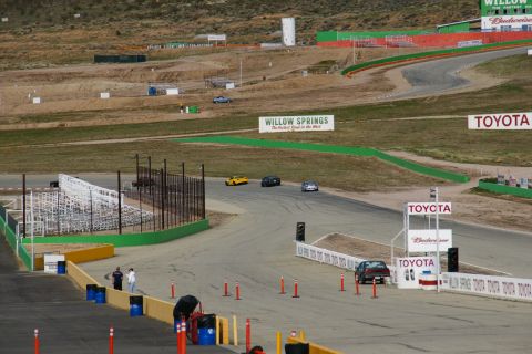 1995 Ford Taurus - A race track scene at Willow Springs, with several cars visible on the track and surrounding facilities.
