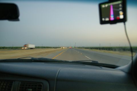 1995 Ford Taurus - Driving on a highway at dusk, with a GPS visible on the dashboard and other vehicles ahead.
