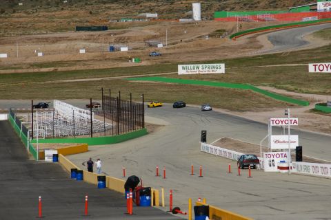 1995 Ford Taurus - Cars race on the track at Willow Springs International Raceway under a clear sky.