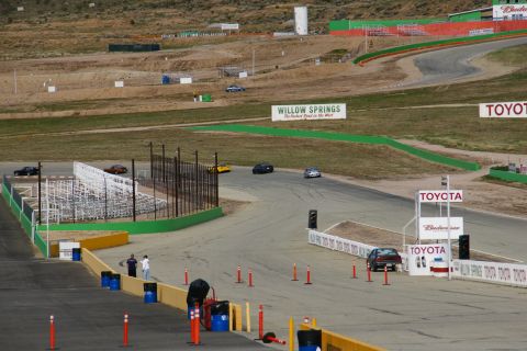 1995 Ford Taurus - A race track scene with multiple vehicles navigating the course under a cloudy sky.