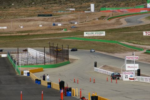 1995 Ford Taurus - A dark sedan navigates a turn on the Willow Springs International Raceway, with Toyota branding visible.