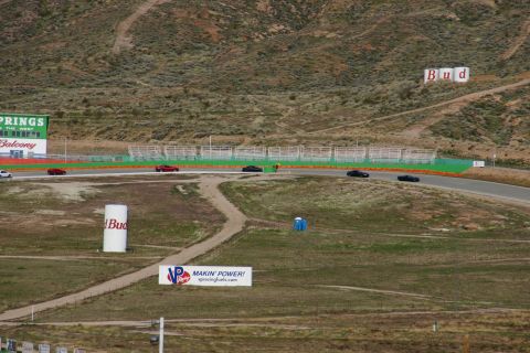 1995 Ford Taurus - Cars are seen on a race track with various signs and a portable toilet in the foreground.