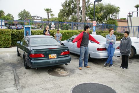 1995 Ford Taurus - Two Ford Tauruses are parked in a lot with several people standing nearby.