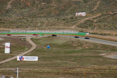 1995 Ford Taurus - Several cars are driving on a winding race track with advertising signs visible.