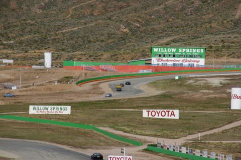 1995 Ford Taurus - Cars race on the track at Willow Springs International Raceway, with the Budweiser Balcony building in the background.