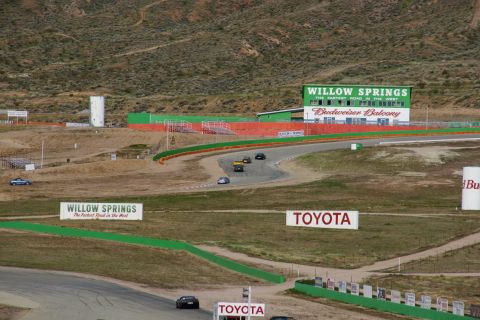 1995 Ford Taurus - Multiple race cars compete on a winding track at Willow Springs International Raceway.