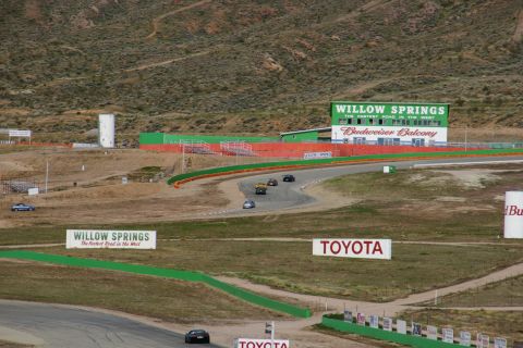 1995 Ford Taurus - Several cars are competing on a winding race track, with the Willow Springs International Raceway visible in the background.