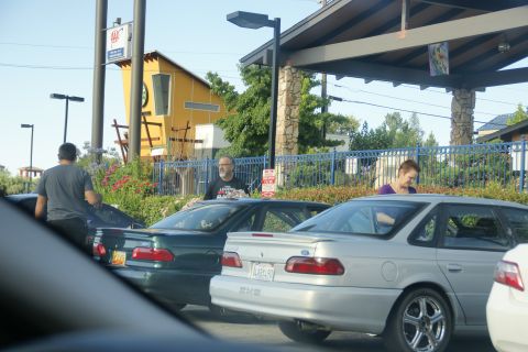 1995 Ford Taurus - Two sedans are parked outside a building with a yellow facade and a covered walkway.
