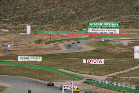 1995 Ford Taurus - A race track scene at Willow Springs, multiple cars in motion and prominent signage for the venue and sponsors.