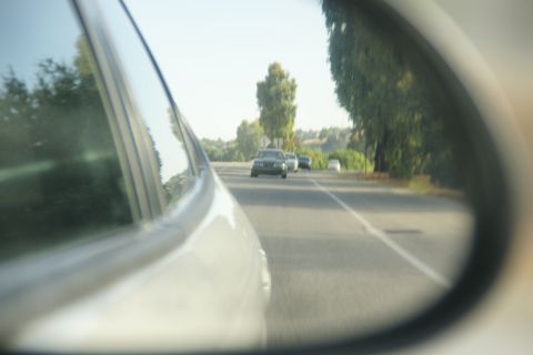 1995 Ford Taurus - A view from a car's side mirror shows traffic on a sunny day.