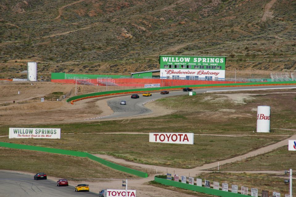 Race track with several cars driving, Willow Springs sign visible