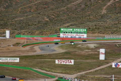 1995 Ford Taurus - Cars race on a track with a building and sponsor signs in the background.
