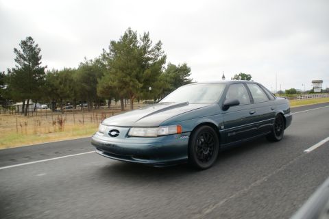 1995 Ford Taurus - This 1995 Ford Taurus is seen from a 3q-front angle, dark green paint and black aftermarket wheels.