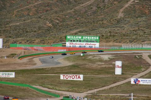 1995 Ford Taurus - Several cars are racing on a track with a large building and various signs visible.