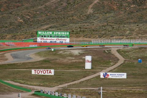 1995 Ford Taurus - Cars race on the track at Willow Springs, with various sponsor signs visible in the background.