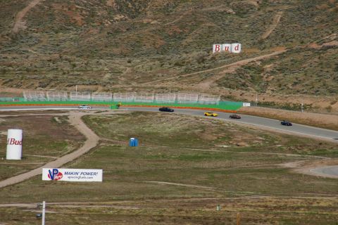 1995 Ford Taurus - A race track scene shows multiple cars navigating the course under a hilly landscape.