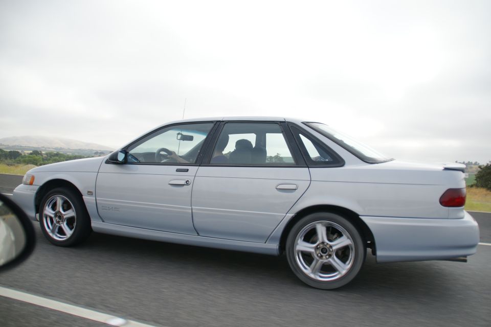 Silver 1995 Ford Taurus sedan driving on highway, side view