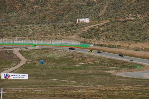 1995 Ford Taurus - A race track scene features multiple cars on the asphalt, a blue portable toilet, and a Budweiser sign visible on the distant hill.