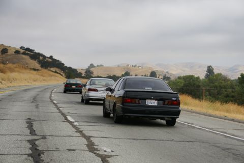 1995 Ford Taurus - A black 1995 Ford Taurus drives on a highway with other vehicles.