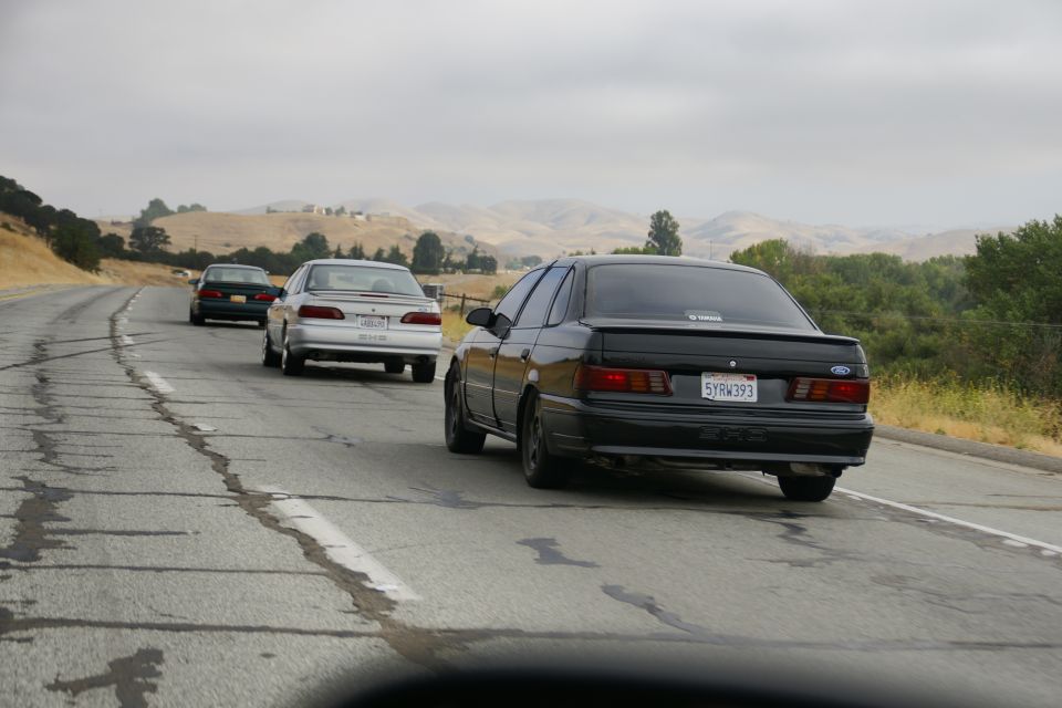 Black Ford Taurus with a spoiler and California license plate 5YRW393 driving on a highway