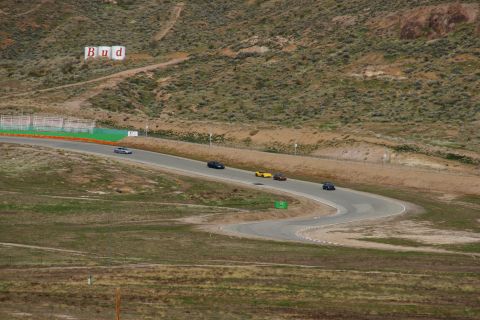 1995 Ford Taurus - Several cars are seen racing on a track in a dry, hilly landscape.