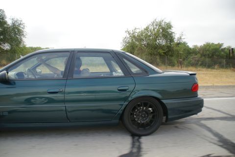 1995 Ford Taurus - Side view of a green 1995 Ford Taurus sedan in motion on a road.