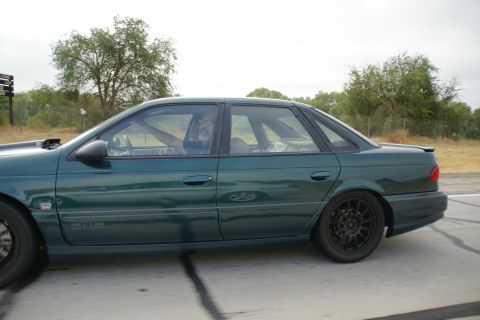 1995 Ford Taurus - A green sedan is seen from the side, with a driver's arm resting on the open window.