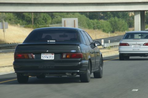 1995 Ford Taurus - Rear view of a black 1995 Ford Taurus SHO driving on the highway.