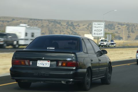 1995 Ford Taurus - Rear view of a black sedan driving on the highway, with a 'SHO' badge visible.