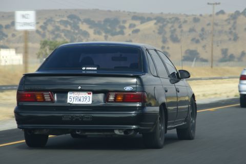 1995 Ford Taurus - Rear view of a black 1995 Ford Taurus SHO driving on a highway.