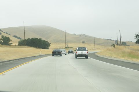1995 Ford Taurus - Vehicles travel on a highway through a dry, hilly landscape under an overcast sky.