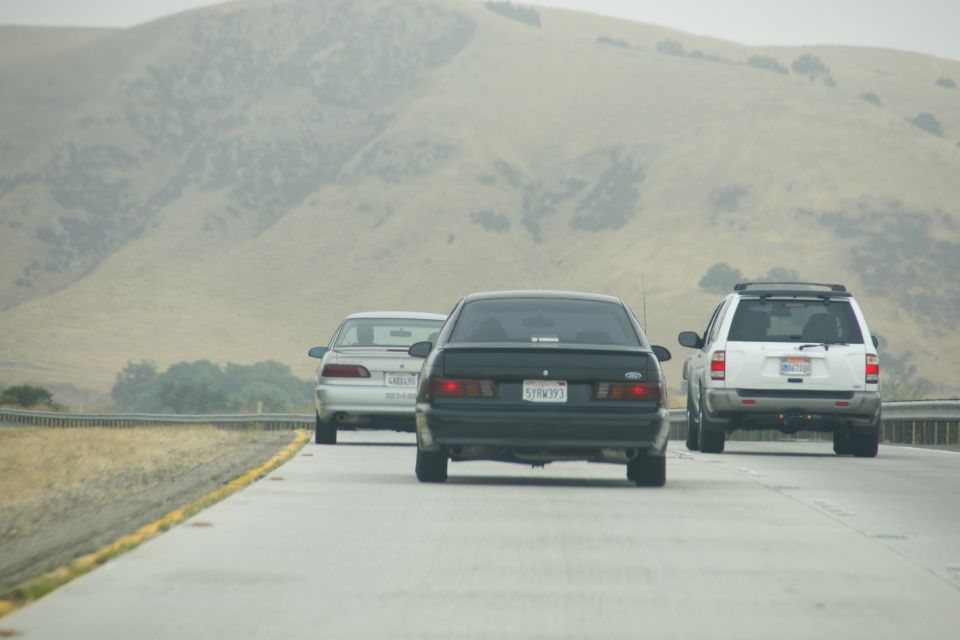 Black sedan from rear, license plate 5YRW393, driving on highway with other vehicles