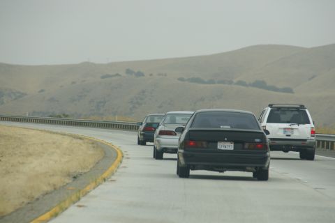 1995 Ford Taurus - Cars travel along a highway under a hazy sky with distant hills.