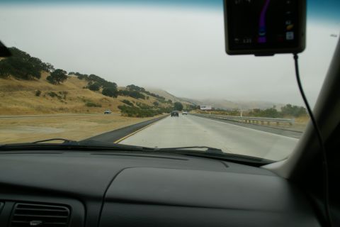 1995 Ford Taurus - View from inside a car traveling on a highway through a hilly landscape under a foggy sky.