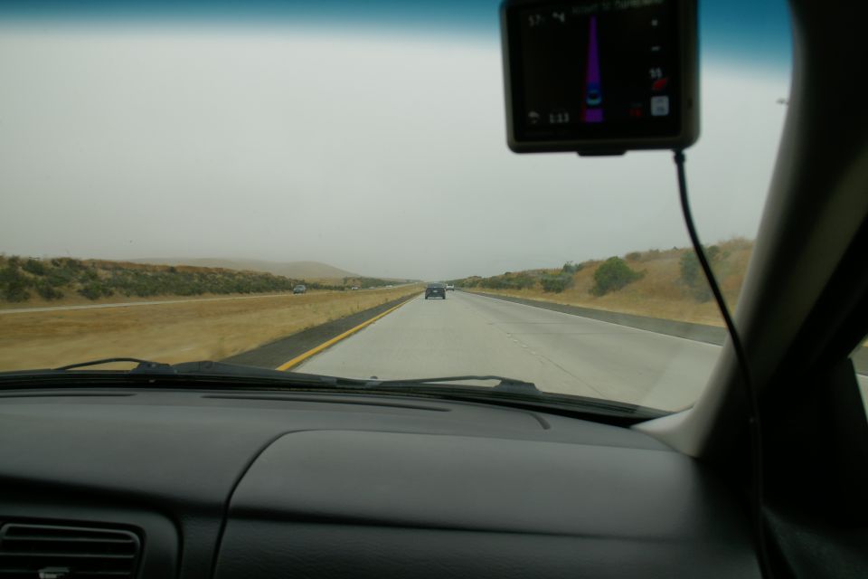Interior view of car dashboard with GPS on windshield, driving on highway