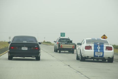 1995 Ford Taurus - Three vehicles drive on a highway under an overcast sky.