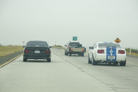 1995 Ford Taurus - Three vehicles drive down a highway under an overcast sky.
