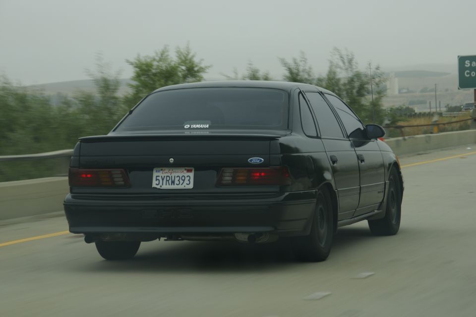 1995 Ford Taurus driving on highway, rear view. California license plate 5YRW393