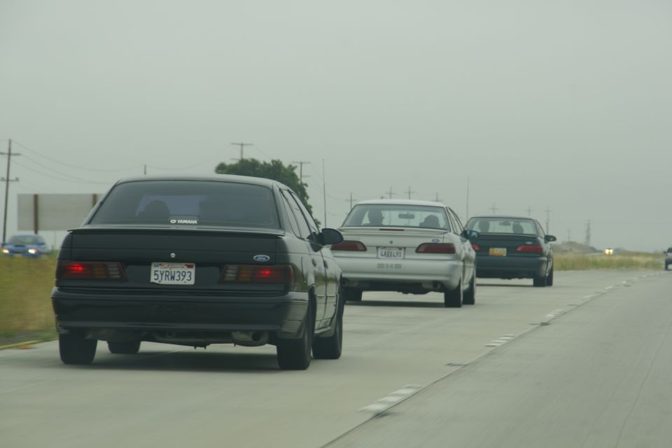 Black 1992 Ford Taurus sedan from rear, license plate 5YRW393, driving on highway
