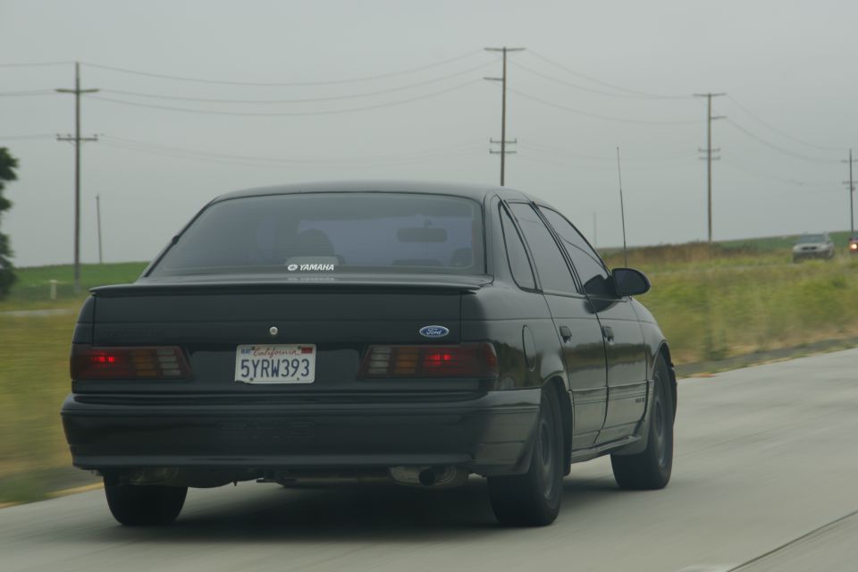 Black 1995 Ford Taurus sedan rear view with California license plate 5YRW393
