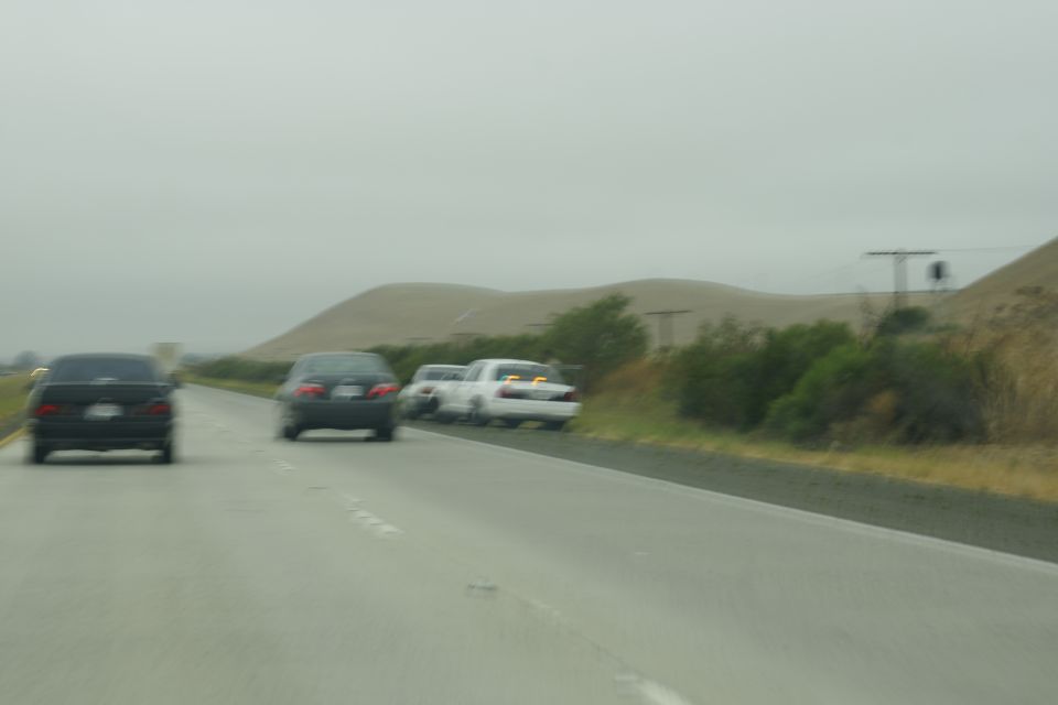 Rear view of three cars on a highway under an overcast sky