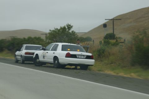 1995 Ford Taurus - Two vehicles stopped on the side of the road, one appears to be a police car with its lights activated.