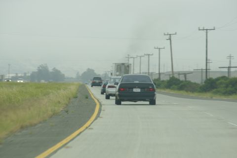 1995 Ford Taurus - Traffic moves along a highway under a hazy sky, with utility poles lining the roadside.
